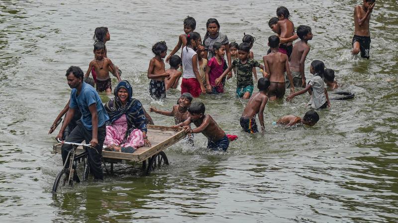 New Delhi: Flood affected people wade through the floodwaters of the swollen Yamuna river near Mayur Vihar after heavy monsoon rainfall, in New Delhi, Wednesday, July 19, 2023. The water level of the Yamuna in Delhi breached the danger mark again on Wednesday morning, less than 12 hours after it dropped below the threshold, amid rains in the national capital and the upper reaches of the river. (PTI Photo/Manvender Vashist Lav)