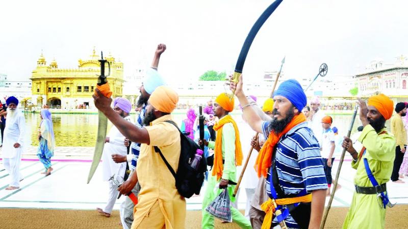 Sikhs hoisting swords at Darbar Sahib.