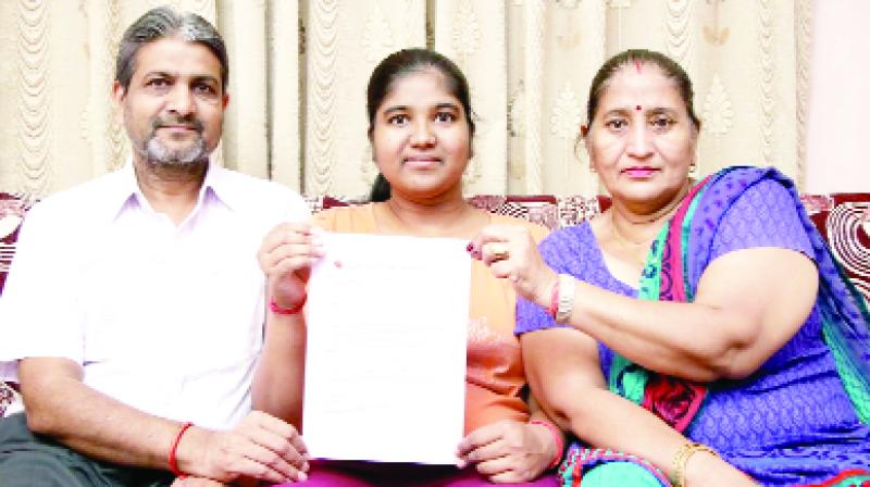 Priya Garg shows a copy of her scholarship with her parents