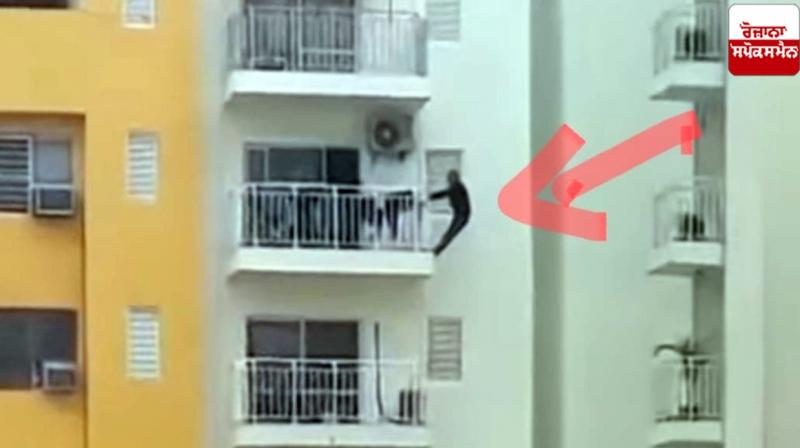 Man doing exercise by hanging from 12th floor balcony