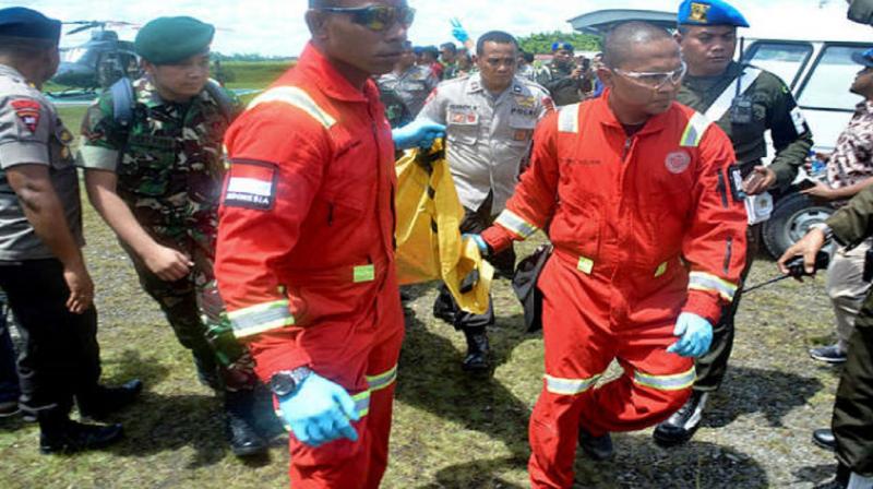 Indonesian military and police officers carry body bags Indonesian military and police officers carry body bags