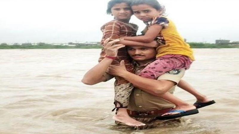 Gujarat police constable carried two children on his shoulders in flood waters?