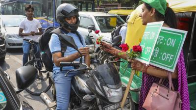 New Delhi: A volunteer presents a flower to a commuter during the launch of 'Red Light On, Gaadi Off campaign' by Delhi Environment Minister Gopal Rai to curb air pollution, at ITO in New Delhi, Monday, Oct. 21, 2024. (PTI Photo)