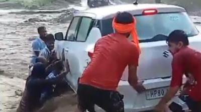  ਹੜ੍ਹ ਦੇ ਪਾਣੀ 'ਚ ਫਸੀ ਕਾਰ ਨੂੰ ਕੱਢਦੇ ਹੋਏ ਲੋਕ