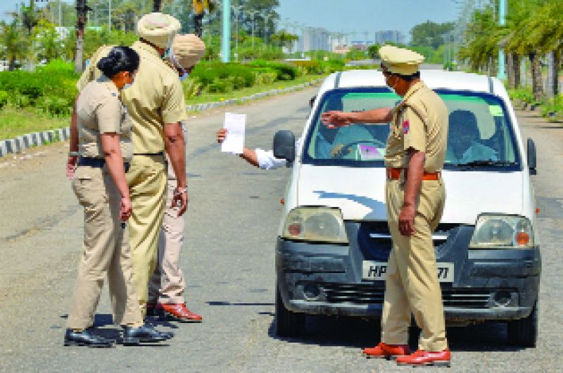 ਚੰਡੀਗੜ੍ਹ 'ਚ ਕਰਫ਼ੀਊ ਦੌਰਾਨ ਇਕ ਕਾਰ ਚਾਲਕ ਨੂੰ ਰੋਕ ਕੇ ਉਸ ਦਾ ਪਾਸ ਵੇਖਦੇ ਪੁਲਿਸ ਮੁਲਾਜ਼ਮ।  ਪੀਟੀਆਈ