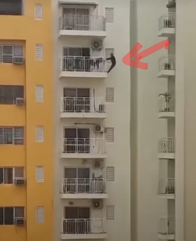 Man doing exercise by hanging from 12th floor balcony